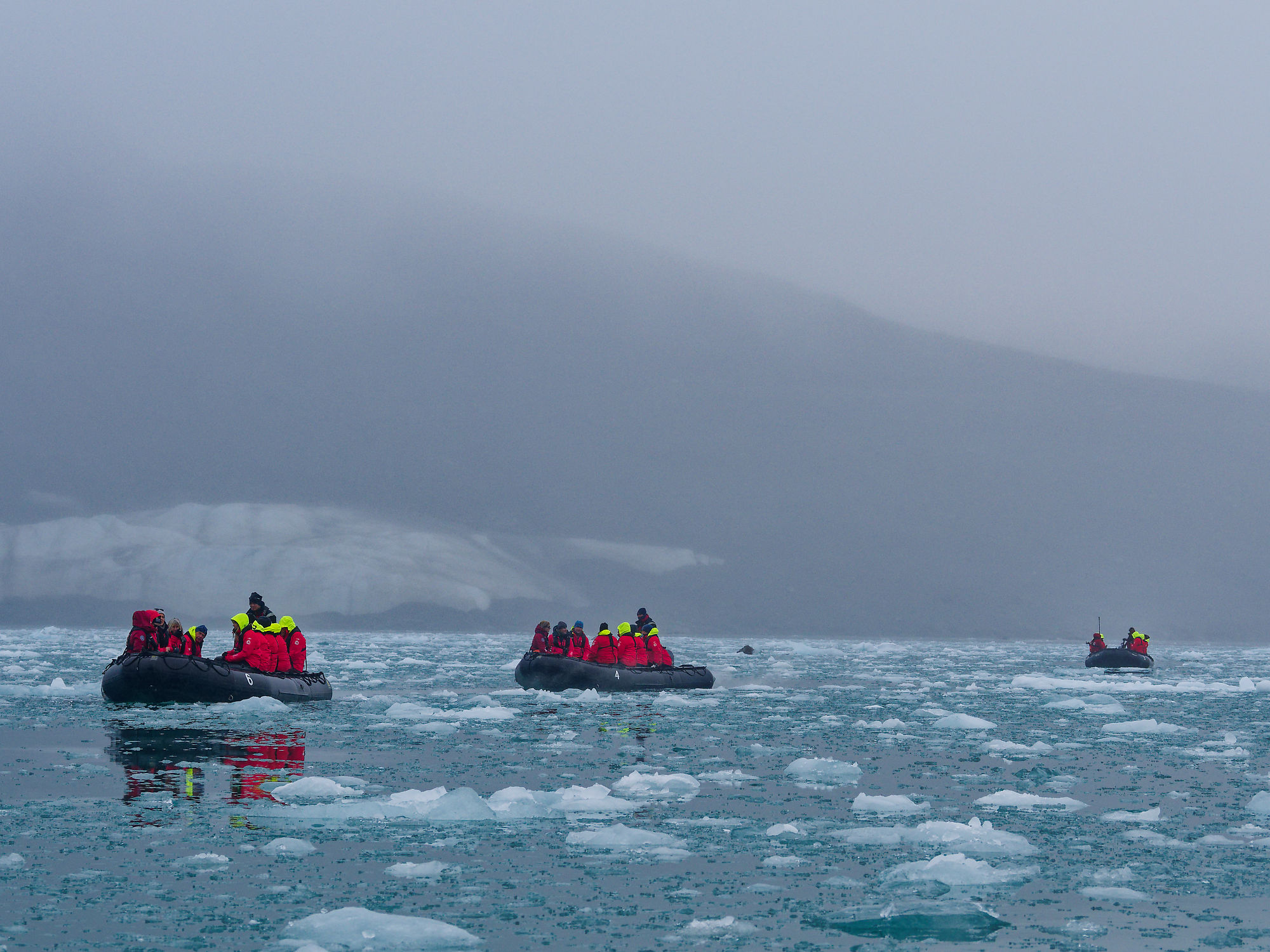 Schlauchboote im Liefdefjorden, Spitzbergen. Eisberge im Wasser, arktische Landschaft mit Touristen.