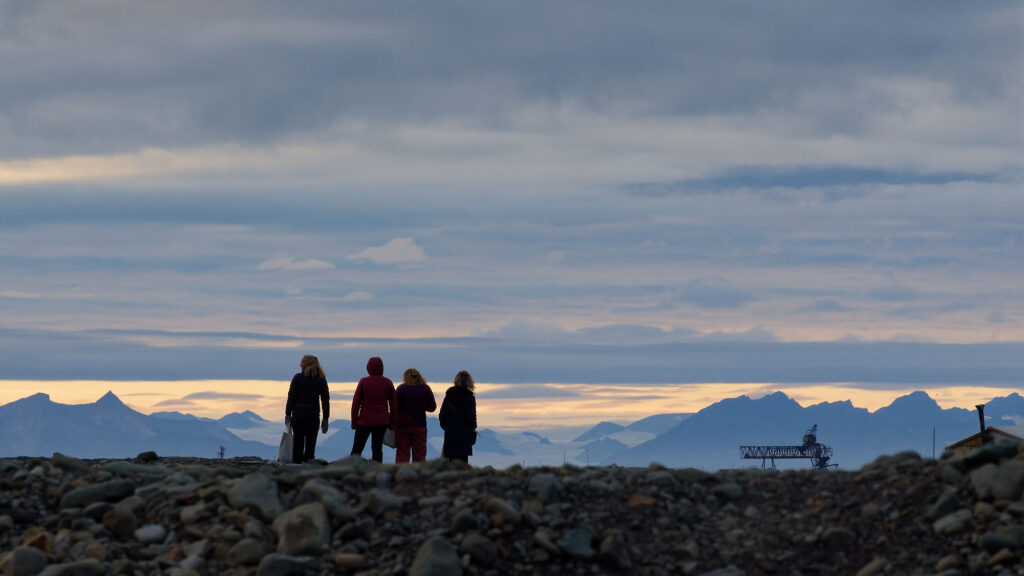 Longyearbyen, Spitzbergen: Gruppe von Wanderern am Hafen in der arktischen Landschaft mit Bergen im Hintergrund.