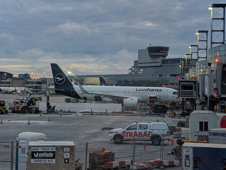 Lovehansa Flugzeug am Flughafen. Lufthansa Maschine am Gate, Tower im Hintergrund.