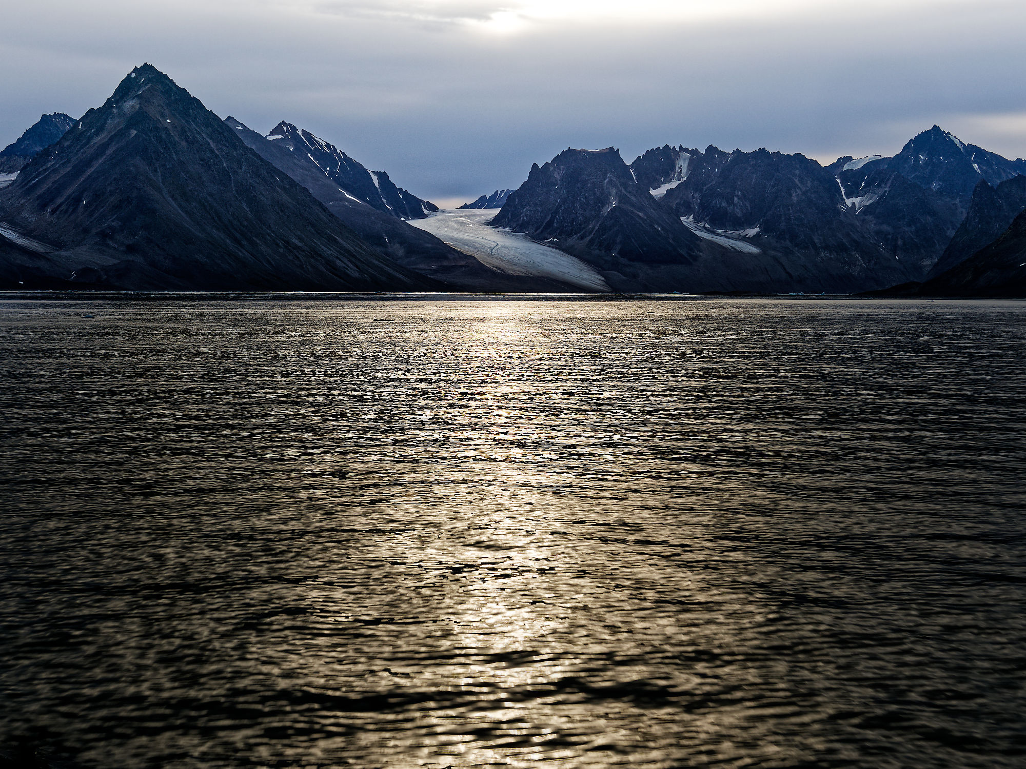 Magdalenefjord, Spitzbergen: Dunkle Berge, Gletscher und Wasser mit Lichtreflexionen. Arktische Landschaft.