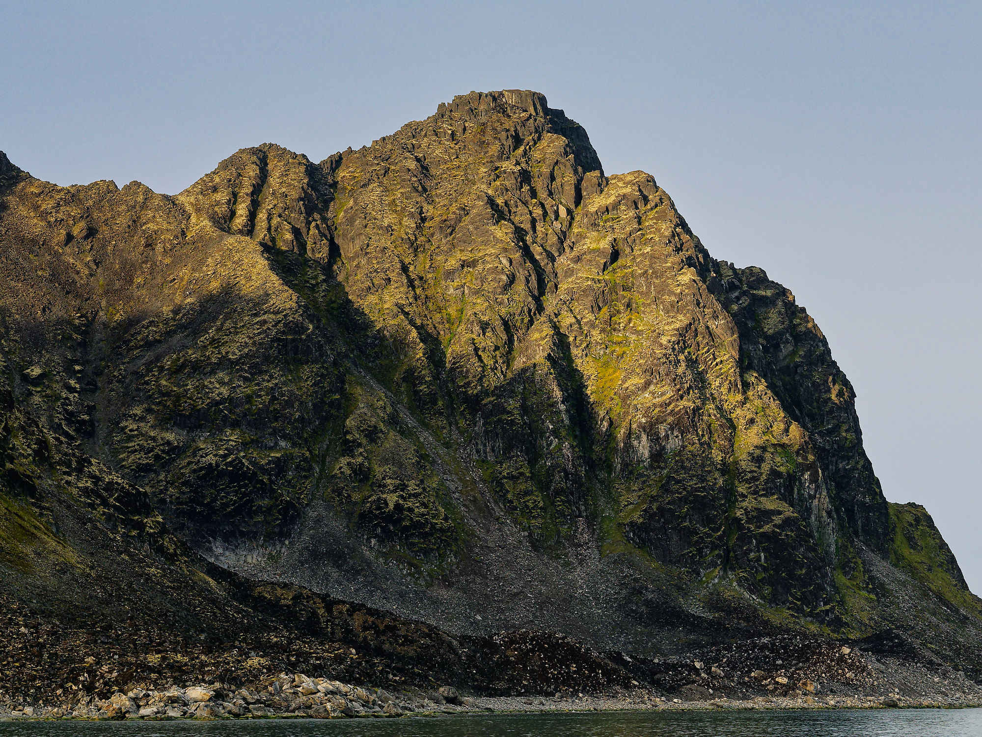 Felsiger Berg im Magdalenefjord, Spitzbergen. Landschaft mit steiler Felswand und Wasser.