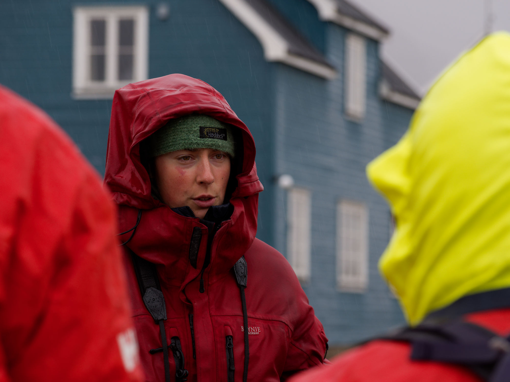 Frau in Ny-Ålesund, Arktis, mit roter Jacke im Regen. Forschungsexpedition.