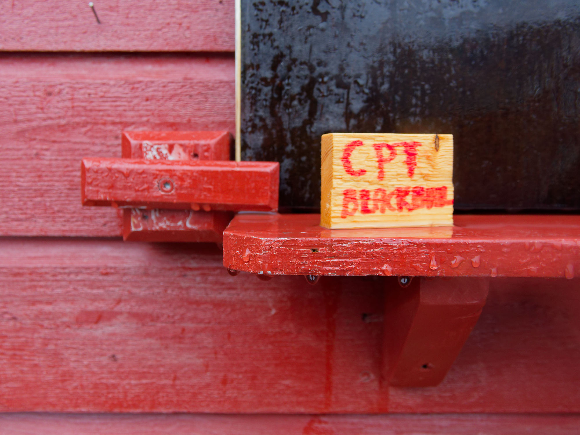 Ny-Ålesund Detail: Rote Wand, Regal mit Holzblock CPT BLACKBURN. Arktis, Spitzbergen.