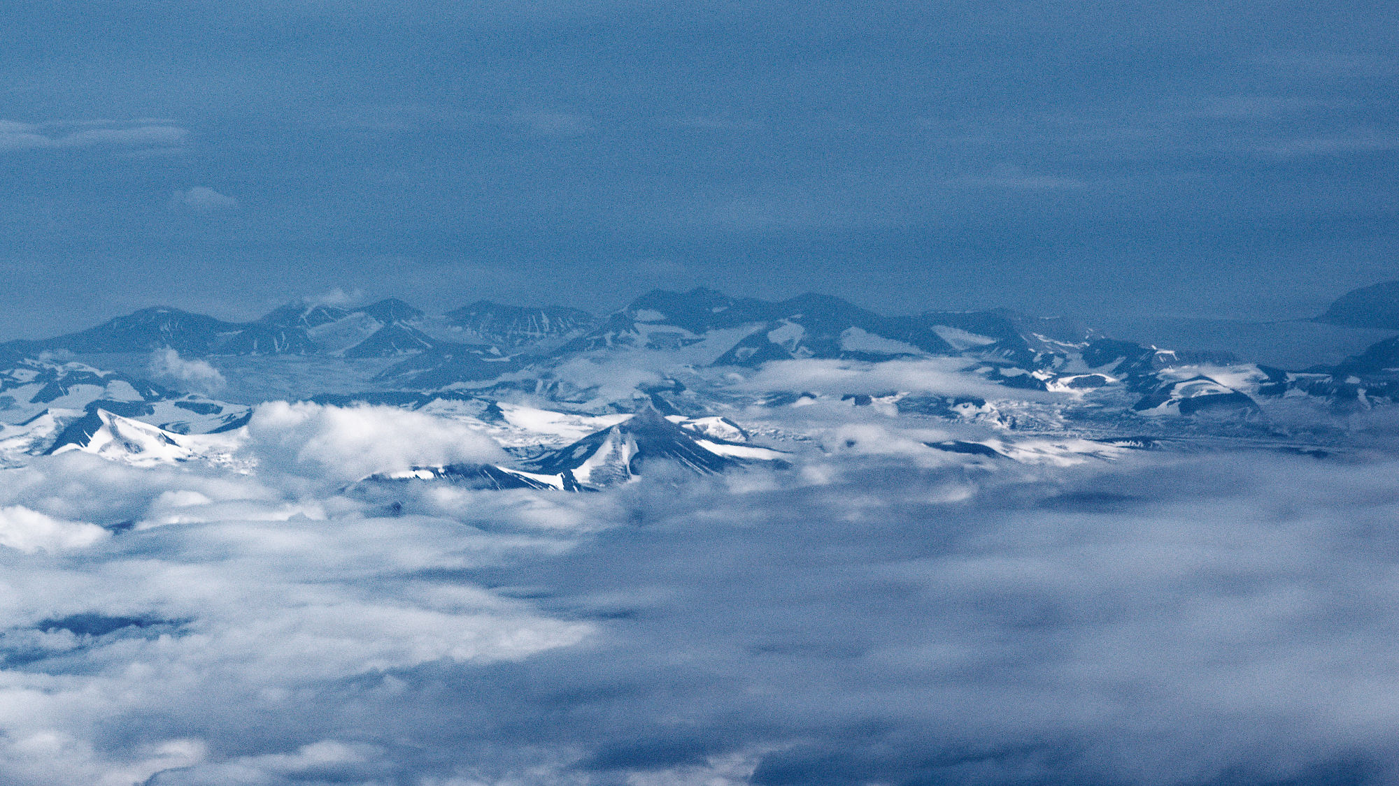 Schneeberge ragen aus Wolken. Winterlandschaft mit Gipfeln.