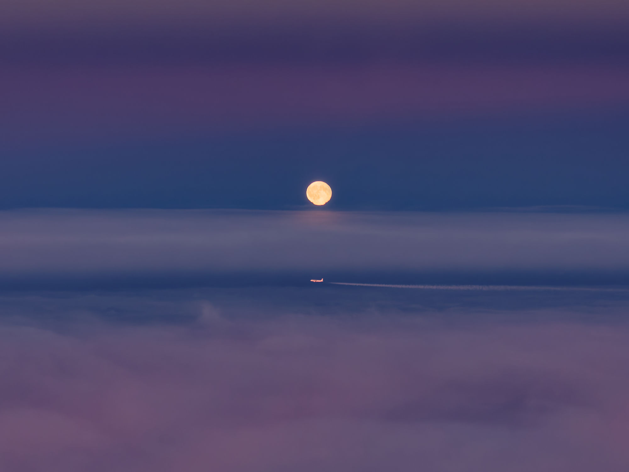 Vollmond über Nebelmeer, Flugzeug am Himmel. Romantische Nachtaufnahme.