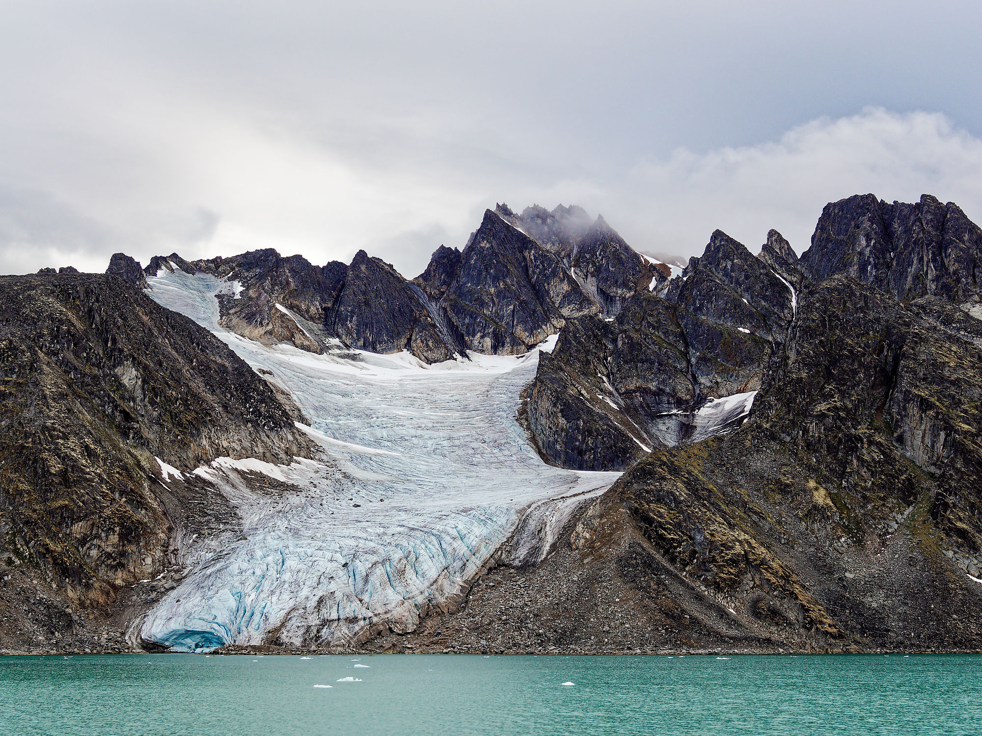 Smeerenburgfjorden, Spitzbergen: Gletscher vor dunklen Bergen und blauem Wasser. Arktische Landschaft.